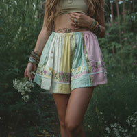 Person wearing a patchwork skirt with floral patterns in a natural setting