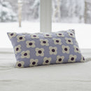 Floral patterned pillow on a woven stool against a white wall