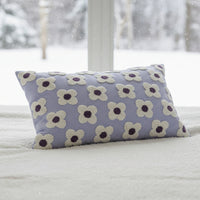 Floral patterned pillow on a woven stool against a white wall