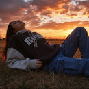 Person lying on grass with a sunset sky