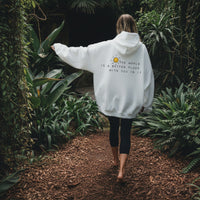 Person wearing a white hoodie with a motivational quote and smiley face design.