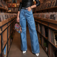 Woman in a black leather top and blue jeans standing in a record store.