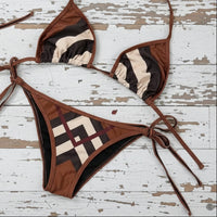 Brown and beige patterned bikini set on a rustic wooden surface