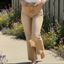Person wearing beige pants standing on a stone pavement with wooden planks in the background