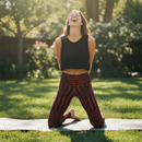 Person wearing red ribbed yoga pants kneeling on a gassy surface with nature background