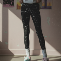 Person wearing black leggings with white star pattern in a room with posters on the wall.