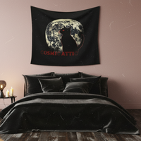 Bedroom with a black tapestry featuring a moon and silhouette hanging above a bed with white bedding and a brown throw.