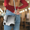 Person wearing a red long-sleeve top and blue jeans, holding a black and white patterned bag.
